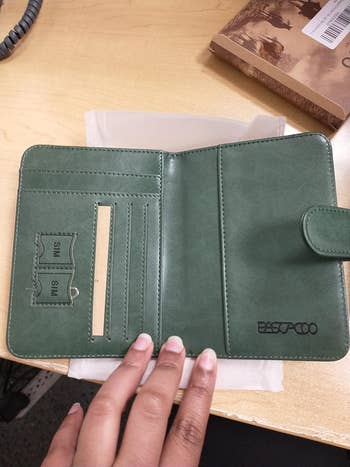 A hand is holding an open green passport holder
