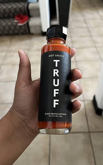 A reviewer holding the bottle of original hot sauce