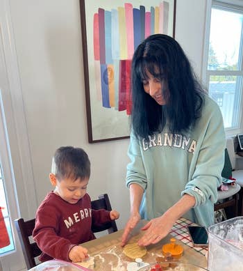 Woman and child making cookies in a kitchen. Woman wears a 