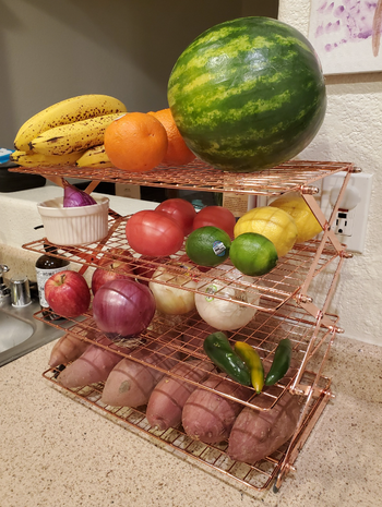 reviewer using four-tier rack to store produce on counter