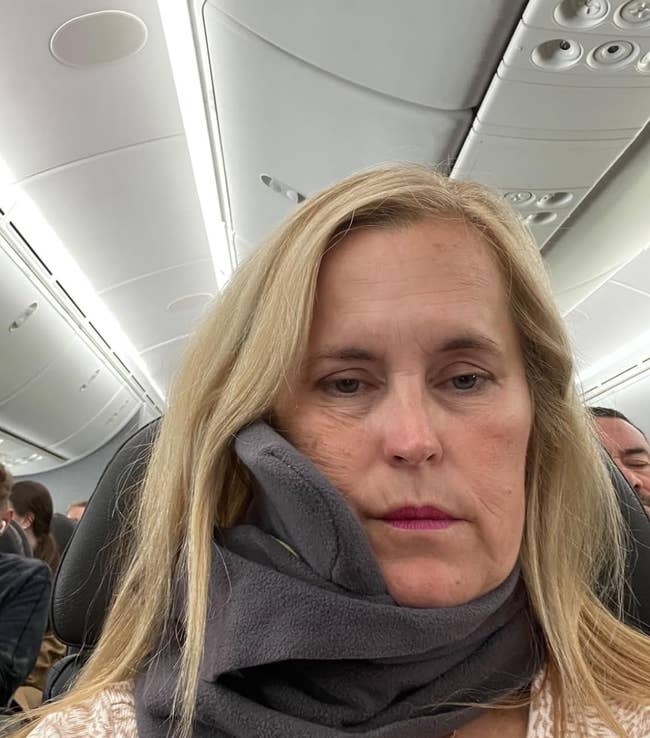 Lifestyle reviewer resting head on plane while wearing the trtl pillow