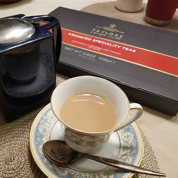reviewer photo of a cup of tea in front of the assorted tea box