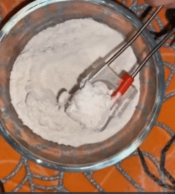 Reviewer using the squeezing mechanism on a tablespoon to level out flour before adding it into a bowl 
