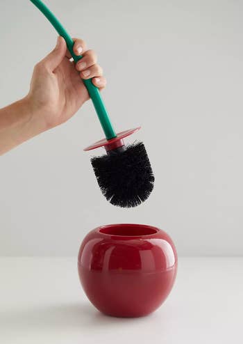 model holding the cherry toilet brush showing its black bristles