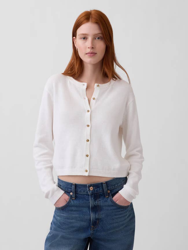 Model wearing a achromatic buttoned harvest cardigan and jeans with hands successful pockets, showcasing casual manner style