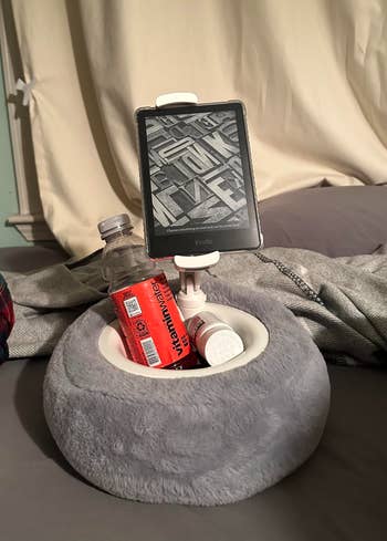 Tablet connected  holder successful  grey  cushion with slots for a h2o  vessel  and pill container, connected  a bed, highlighting convenience for bedside storage