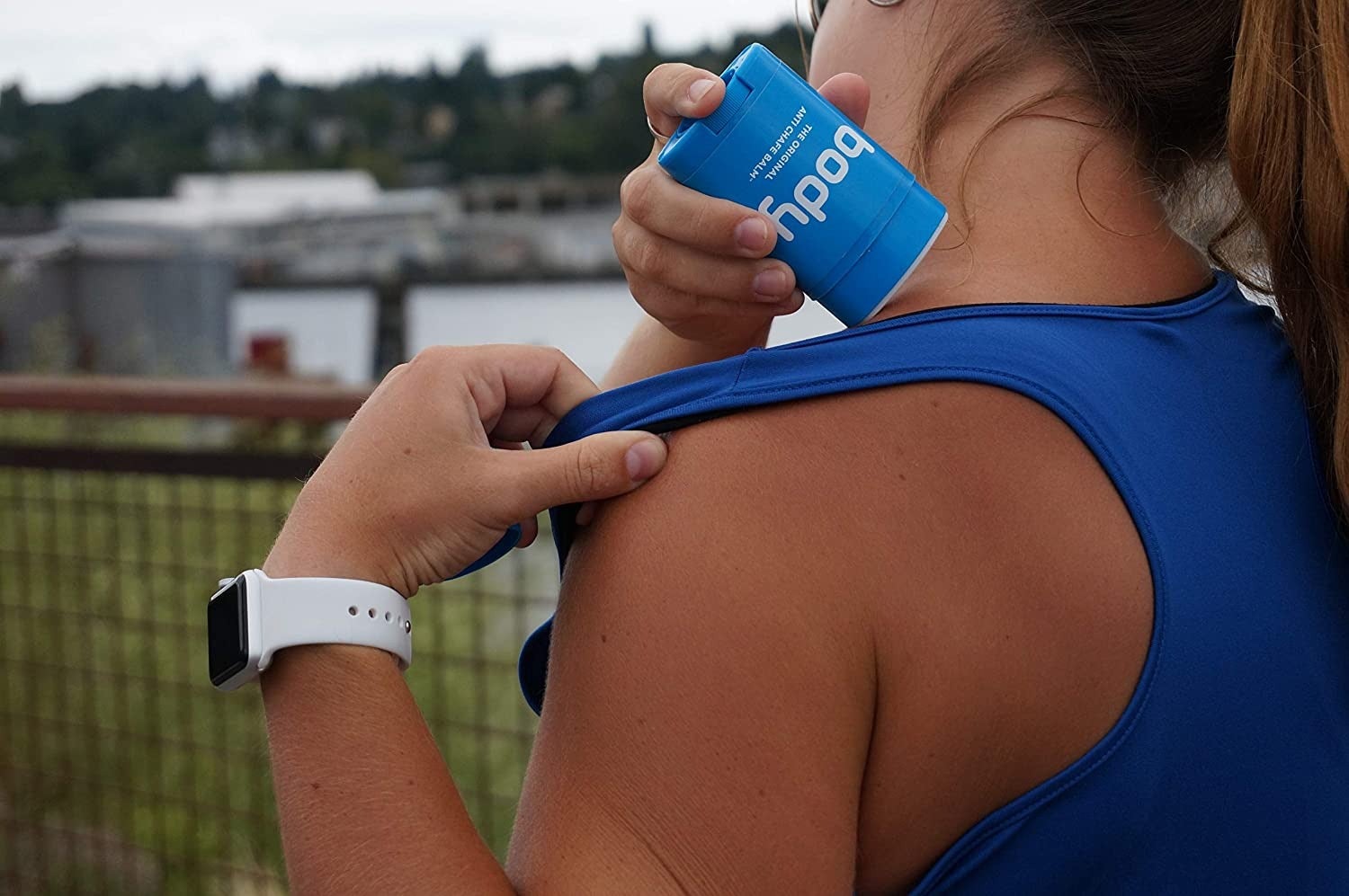 a model putting the balm under their tank top strap