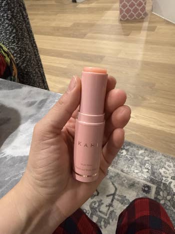 Hand holding a Kahi Multi Balm stick, a skincare merchandise  for moisturizing and enhancing skin, perfect  for an on-the-go quality   regimen