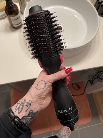 reviewer photo of them holding the black and pink blow dry brush