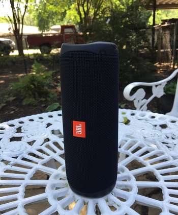 reviewer photo of the black speaker resting on one of its ends on an outdoor table