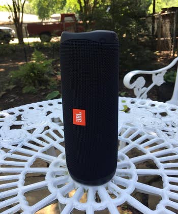 reviewer photo of the black speaker resting on one of its ends on an outdoor table