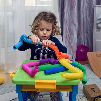 a child model connecting blue and orange pop sensory tubes