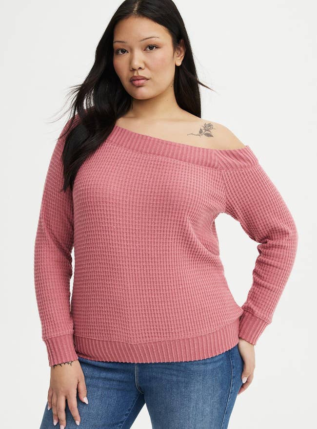 Model wearing a textured off-shoulder apical and jeans, lasting with 1 manus connected hip