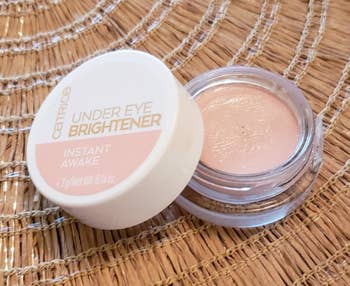 Wadah Catrice Under Eye Brightener pada permukaan anyaman