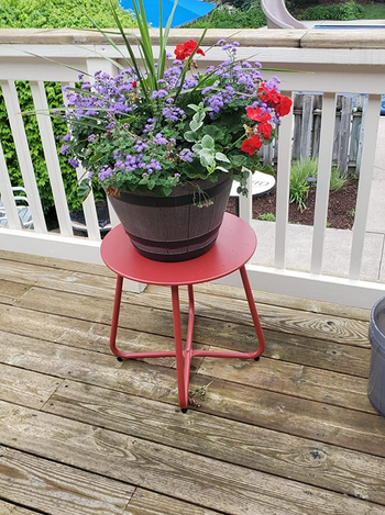 Reviewer photo of the table in red with a pot of flowers sitting on it on a deck 