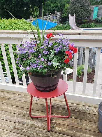 Reviewer photo of the table in red with a pot of flowers sitting on it on a deck 