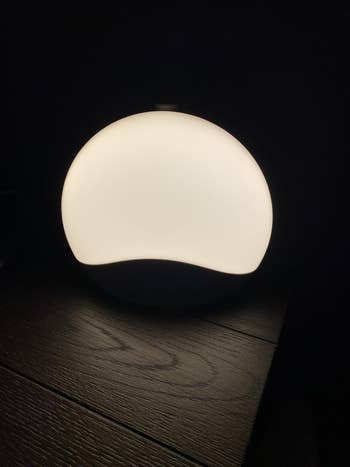 Modern lamp with a smooth, circular  plan  casting brushed  airy  connected  a woody  surface. Ideal for minimalist location  decor