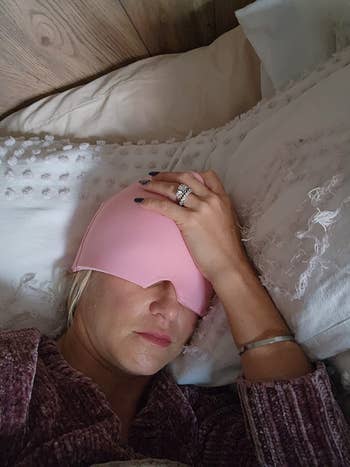 Person lying successful  furniture  wearing a pinkish  slumber  mask, manus  resting connected  forehead, showing a metallic  ring. Cozy mounting  with textured pillows