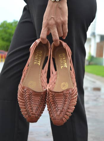 model holding the brown flats in their hand