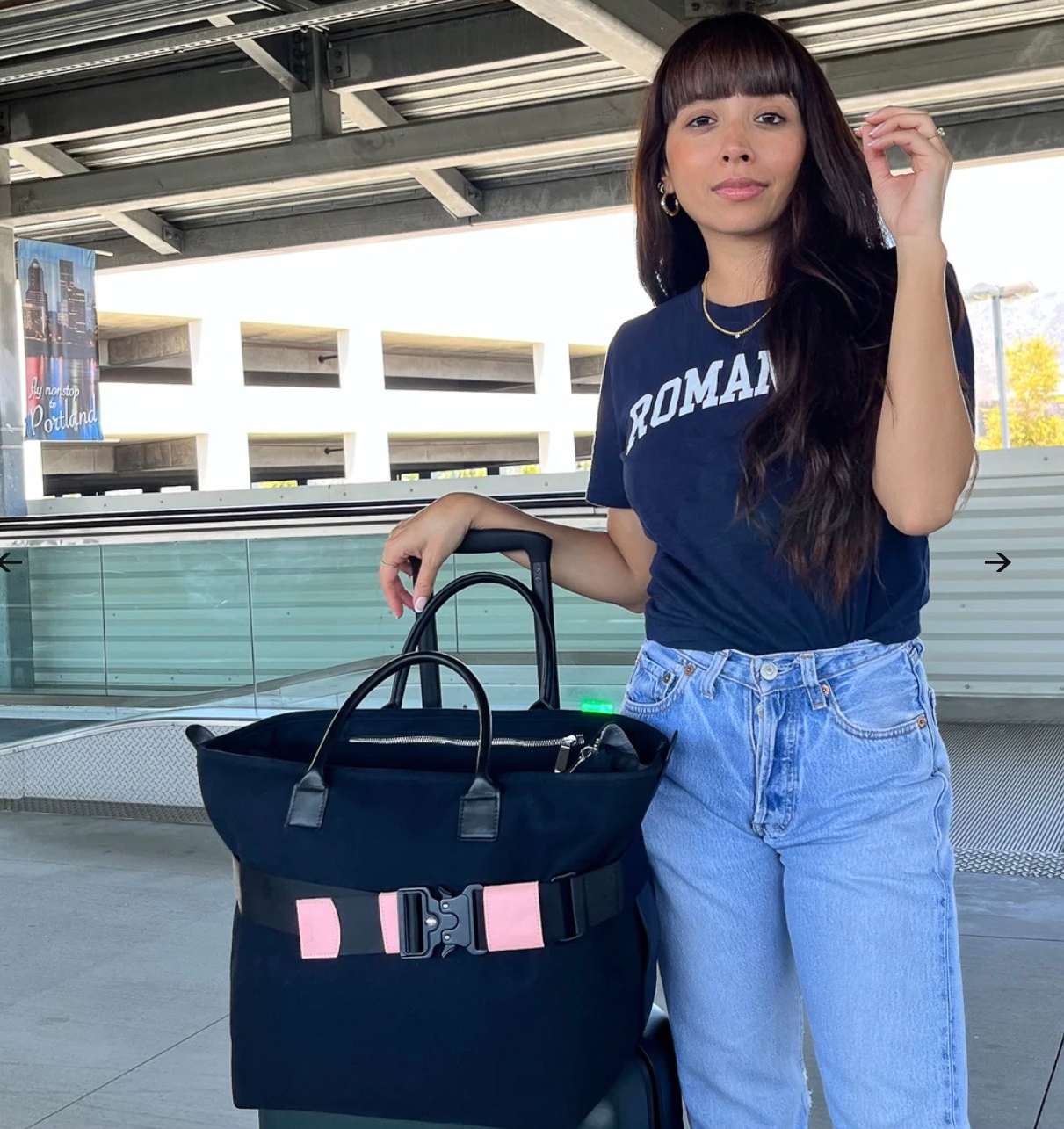 pink and black adjustable travel belt around navy blue tote bag on top of suitcase