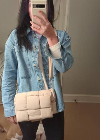 reviewer posing with the beige puffer bag