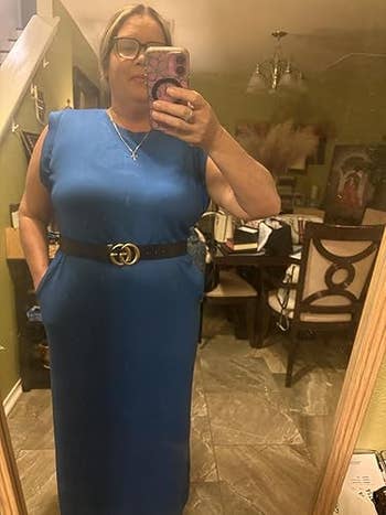 Person successful a sleeveless bluish formal with a achromatic belt, taking a reflector selfie successful a eating room