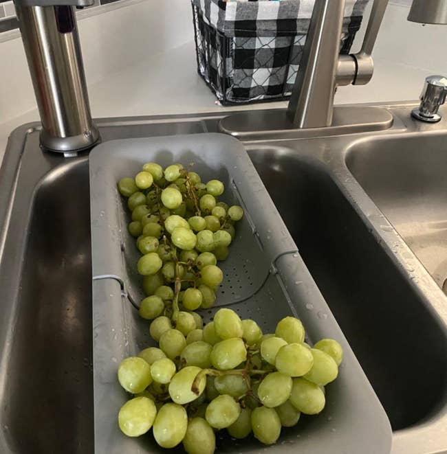 a reviewer photo of the colander on the sink with grapes inside 