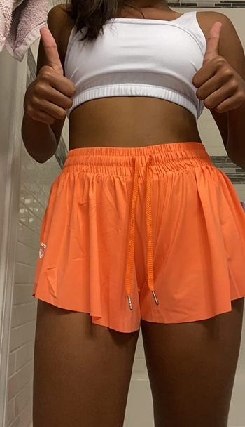 a reviewer wearing the shorts in orange 