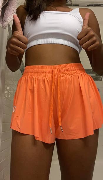 a reviewer wearing the shorts in orange 
