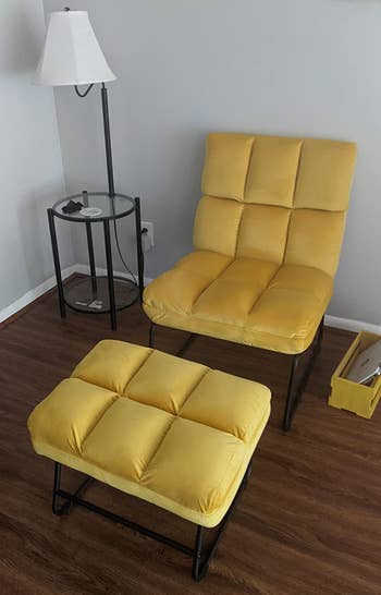 Reviewer image of tufted yellow velvet armless lounge chair with matching ottoman and black metal legs on a hardwood floor