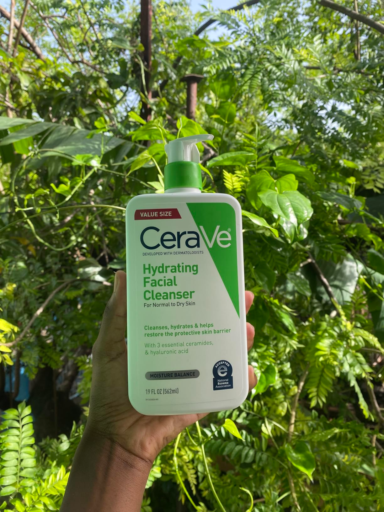 A reviewer holding the CeraVe hydrating facial cleanser