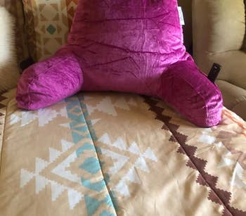 magenta pillow on bed with two arms