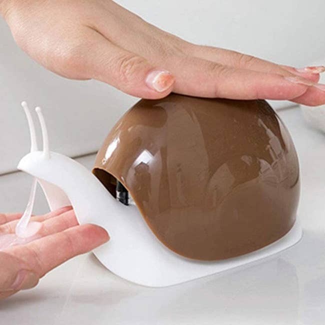 person getting soap from a snail-shaped soap dispenser