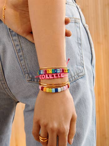 model in pink name bracelet stacked with other bracelets