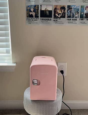 reviewer photo of the pink mini fridge on a stool