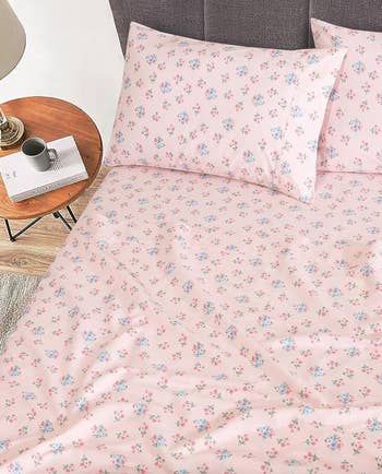 Floral patterned bedding set displayed on a bed with a side table and mug