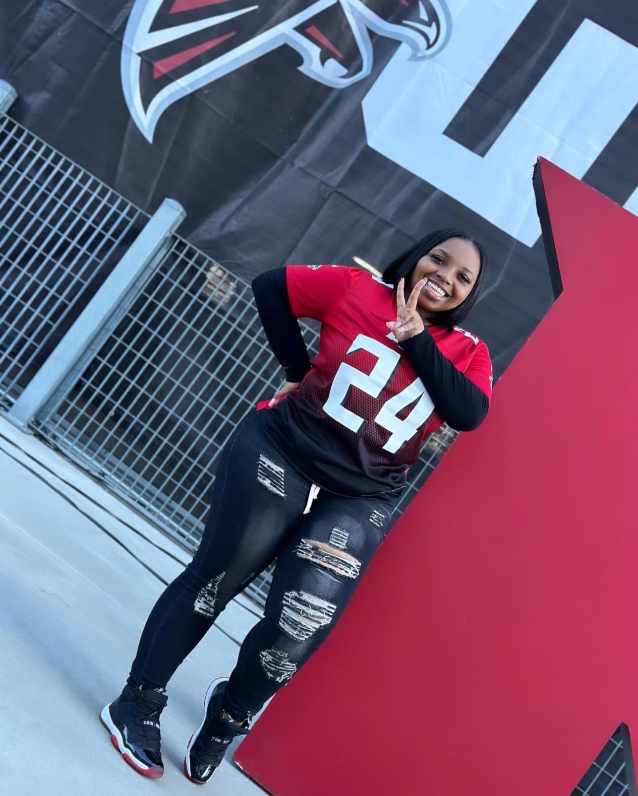 Person successful  a shot   jersey and distressed jeans poses smiling with a bid    motion   adjacent   a ample  structure