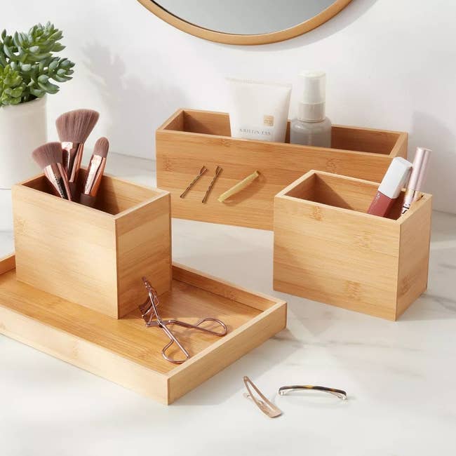 the wooden organizer holding a makeup brushes, lip gloss and other beauty items