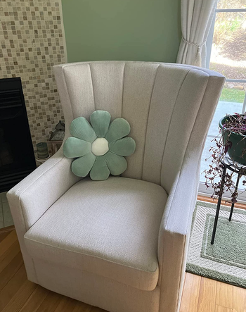 Blue daisy shaped pillow perched on an armchair