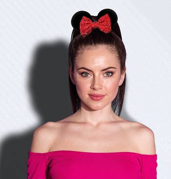 a model wearing a high pony tail with black mouse ears and a red bow