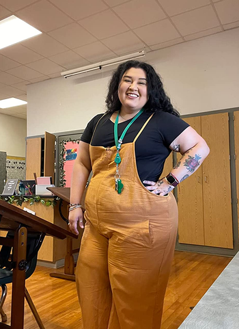 a reviewer wearing the same overalls in mustard yellow over a black T-shirt 
