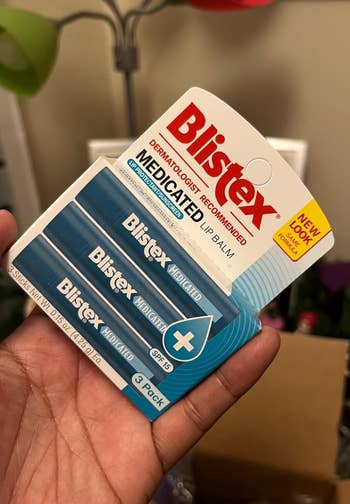 Person holding a 3-pack of Blistex medicated articulator  balm, featuring SPF 15 extortion  and dermatologist proposal   connected  the packaging