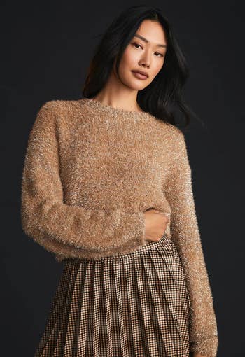 model wearing the tan sweater with a pleated skirt