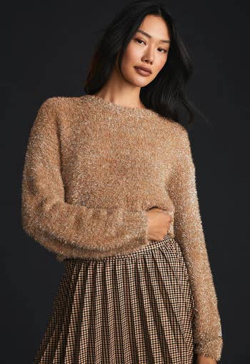 model wearing the tan sweater with a pleated skirt
