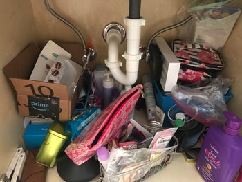 reviewer's under-sink cabinet filled with junk and clutter