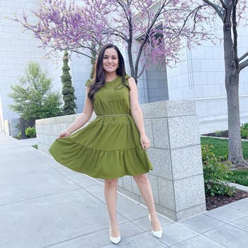 reviewer wearing the green dress with white pointed heels