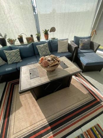 Living country   with a modern   couch, geometric-patterned cushions, java  array  with woven basket, and decorative plants connected  the side