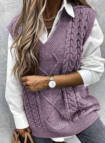 a model wearing a purple cable knit vest over a white button-down blouse