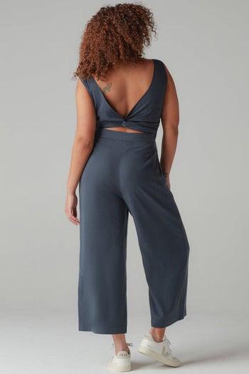 model showing the jumpsuit twisted in the back in navy