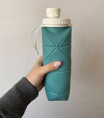 Reviewer holding dark green water bottle with geometric indents 